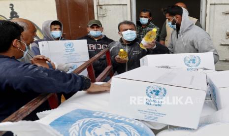 Pekerja Palestina memuat persediaan makanan yang didistribusikan oleh Badan Bantuan dan Pekerjaan PBB (UNRWA). Pria berusia 61 tahun telah meninggal di Jalur Gaza akibat Covid-19. Ilustrasi.