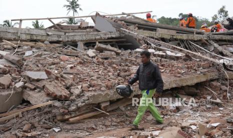 Enjot, 45, yang kehilangan rumah dan beberapa kerabatnya, berjalan melewati puing-puing bangunan yang runtuh akibat gempa Senin di Cianjur, Jawa Barat, Indonesia Selasa, 22 November 2022. Tim penyelamat pada Selasa berjuang untuk menemukan lebih banyak mayat dari puing-puing rumah dan bangunan roboh akibat gempa bumi yang menewaskan sejumlah orang dan melukai ratusan orang di pulau utama Indonesia di Jawa.