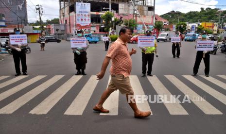 Anggota Polsek Tikala memegang spanduk imbauan di ruas jalan di Manado, Sulawesi Utara, Senin (30/3). (ilustrasi)