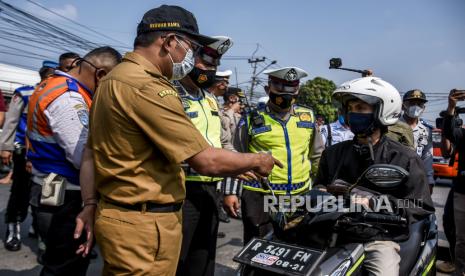 Gubernur Jawa Barat Ridwan Kamil berbincang dengan pengendara kendaraan dengan plat nomor luar Bandung saat melakukan pemantauan posko penyekatan larangan mudik di gerbang Tol Padalarang, Kabupaten Bandung Barat, Senin (10/5). Pada hari kelima penerapan larangan mudik Lebaran 2021, petugas gabungan di posko penyekatan larangan mudik Padalarang telah memutarbalikan sedikitnya 30 kendaraan berplat luar kota karena tidak memiliki surat kesehatan serta ijin perjalanan. Foto: Republika/Abdan Syakura