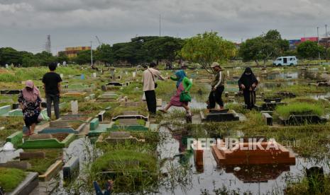 Warga melakukan ziarah kubur keluarganya di tempat pemakaman umum (TPU) yang terendam air di TPU Semper, Jakarta Utara, Ahad (3/3/2024). Tradisi ziarah kubur dilakukan umat Islam jelang bulan Ramadan yang akan jatuh sekitar sepekan ke depan. Kegiatan tersebut dilakukan untuk mendoakan keluarga yang sudah meninggal, sekaligus merawat makamnya meski dalam kondisi terendam.