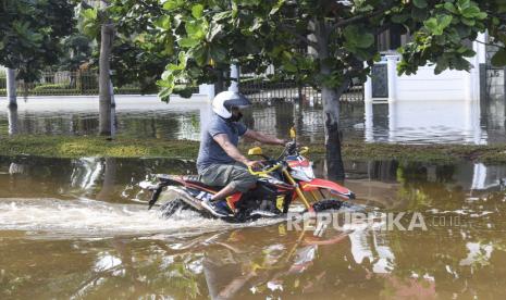 Pengendara motor melintas saat banjir rob ilustrasi