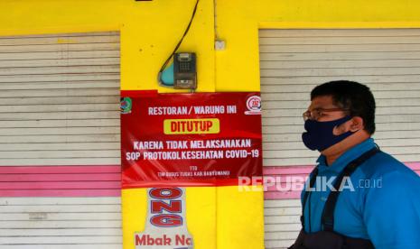 Warga melintas di depan warung makan yang ditutup di Banyuwangi, Jawa Timur, Senin (13/7/2020). Gugus tugas percepatan penanganan COVID-19 Banyuwangi memberikan sanksi penutupan selama tiga hari kepada pemilik warung dan toko yang tidak melaksanakan protokol kesehatan. ANTARA FOTO/Budi Candra Setya/pras.