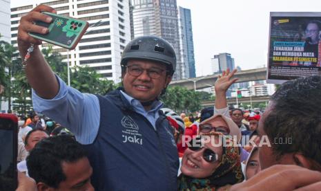 Gubernur DKI Jakarta Anies Baswedan (kiri) berswafoto dengan warga saat bersepeda pada Hari Bebas Kendaraan Bermotor (HBKB) di Jalan Jenderal Sudirman, Jakarta, Ahad (16/10/2022). Anies Baswedan bersepeda dari Lebak Bulus hingga Balai Kota untuk menyapa warga pada hari terakhir menjabat sebagai Gubernur DKI Jakarta. 