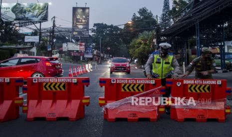 Anggota kepolisian menutup akses jalan Perbatasan menuju Kota Bandung dari Kabupaten Bandung Barat-Subang  di kawasan Ledeng, Bandung, Jawa Barat, Ahad (18/7/2021). Penjagaan akses menuju Kota Bandung di kawasan perbatasan terus dilakukan selama PPKM Darurat guna mencegah penyebaran COVID-19 dan mengantisipasi lonjakan mobilitas warga untuk antispasi mudik dan wisata jelang Hari Raya Idul Adha 1442 Hijriah. 