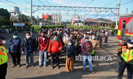 Sejumlah penumpang KRL Commuter Line antre menunggu kedatangan kereta di Stasiun Bogor, Jawa Barat, Senin (13/4/2020). Antrean panjang penumpang KRL Commuter Line di Stasiun Bogor tersebut akibat kebijakan pemeriksaan suhu tubuh dan pembatasan jumlah penumpang di setiap rangkaian kereta sebagai tindakan pencegahan penyebaran wabah pandemi virus corona (covid-19)