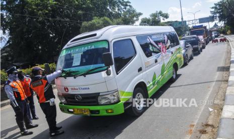 Petugas Dinas Perhubungan menempelkan stiker sosialisasi larangan mudik saat berjaga di Kedungwaringin, Kabupaten Bekasi, Jawa Barat, Ahad (3/5/2020). Penjagaan dilakukan untuk melarang pemudik dari kawasan Jabodetabek melintasi wilayah Bekasi