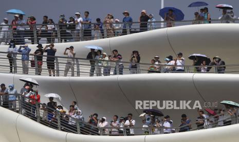 Orang-orang berdiri di jembatan menyaksikan perlombaan perahu naga saat Festival Perahu Naga di sebuah kanal di Tongzhou, pinggiran Beijing, Senin, 10 Juni 2024. 