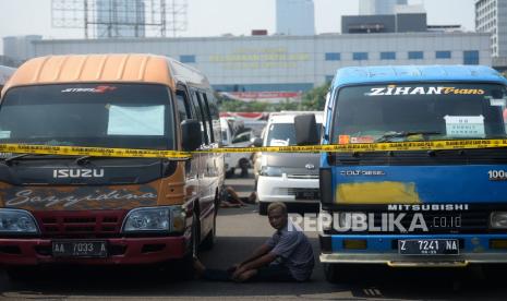 Pengemudi kendaraan travel gelap berada didekat kendaraanya yang terparkir di halaman Polda Metro Jaya, Jakarta, Kamis (29/4). Direktorat Lalu Lintas Polda Metro Jaya mengamankan sebanyak 115 kendaraan travel gelap yang diduga kuat mengangkut pemudik. Kendaraan yang diamanakan tersebut tertangkap tangan sedang membawa penumpang untuk tujuan Jawa Tengah, Jawa Barat dan juga Jawa Timur. Seluruh kendaraan tersebut berpelat hitam dan tidak memiliki izin trayek untuk tujuan tertentu.Prayogi/Republika. 