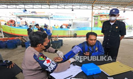 Sejumlah nelayan mengikuti proses vaksinasi COVID-19 usai melakukan bongkar muat ikan di tempat pelelangan ikan Karangsong, Indramayu, Jawa Barat, Senin (6/12/2021). Vaksinasi COVID-19 bagi nelayan itu digelar untuk mengejar herd immunity atau kekebalan kelompok tuntas pada Desember 2021 dengan target 32 juta jiwa untuk wilayah Jawa Barat. 