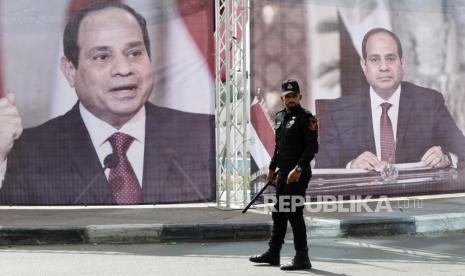 Seorang petugas polisi Hamas berjaga di alun-alun utama di depan potret besar Presiden Mesir Abdel Fattah el-Sissi, sementara para pemimpin Hamas bertemu dengan kepala intelijen Mesir Abbas Kamel, tak terlihat, di Kota Gaza, Senin, 31 Mei 2021.