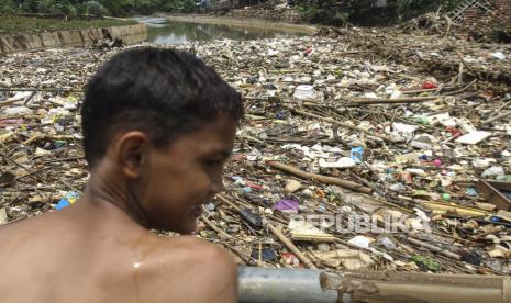 Seorang bocah melihat sampah yang terbawa aliran air dan menyangkut di salah satu jembatan di Kali Pesanggrahan, Cipayung, Depok, Jawa Barat, Jumat (11/3/2022). Sampah menyangkut tersebut membuat aliran air kali terhambat dan menyebabkan banjir di kawasan itu. 