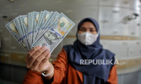 Petugas menunjukan uang dolar AS di tempat penukaran valuta asing.