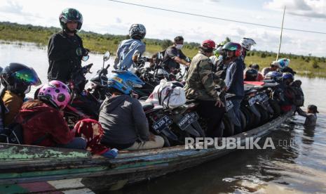 Warga memanfaatkan jasa transportasi perahu bermesin tradisional untuk menyeberangi banjir di jalan trans Kalimantan Bukit Rawi, Pulang Pisau, Kalimantan Tengah, Senin (13/9/2021). Jasa penyeberangan musiman dengan tarif Rp30 ribu hingga Rp70 ribu tersebut digunakan warga sebagai alternatif melintasi banjir luapan Sungai Kahayan yang merendam di jalan nasional Kalimantan itu sejak satu minggu terakhir. 