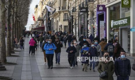  Orang-orang yang memakai masker wajah untuk melindungi diri dari COVID-19 berjalan di sepanjang jalan Champs Elysees di Paris, Rabu, 5 Januari 2022. Prancis mengizinkan petugas kesehatan yang terinfeksi virus corona tetapi memiliki sedikit atau tanpa gejala untuk tetap merawat pasien daripada isolasi mandiri, tindakan jeda luar biasa yang bertujuan untuk mengurangi kekurangan staf di rumah sakit dan fasilitas medis lainnya yang disebabkan oleh ledakan infeksi yang belum pernah terjadi sebelumnya.