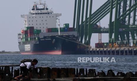 Warga melintas berlatar belakang proses bongkar muat peti kemas di New Priok Container Terminal One, Jakarta Utara, Ahad (19/9). Kementerian Perdagangan (Kemendag) menyatakan, tren pemulihan ekonomi Indonesia kembali berlanjut pascagelombang kedua pandemi Covid-19. Hal ini tergambar dari neraca perdagangan September 2021 yang kembali mencatatkan surplus 4,37 miliar dolar AS. 