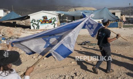 Maroko Tolak Normalisasi dengan Israel karena Kejahatan. Foto:   Pemukim Israel membawa bendera di pos terdepan Eviatar dekat kota Nablus di Tepi Barat utara, Senin, 21 Juni 2021. Pemukim mendirikan pos terdepan bulan lalu dan mengatakan sekarang menjadi rumah bagi puluhan keluarga. Palestina mengatakan itu dibangun di atas tanah pribadi dan khawatir itu akan tumbuh dan bergabung dengan pemukiman besar lainnya di dekatnya.