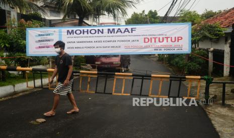 Seorang warga melintas di depan portal jalan yang ditutup di Komplek Pondok Jaya, Mampang Prapatan, Jakarta, Senin (30/3/). Komplek tersebut mulai memberlakukan akses satu pintu masuk utama dan menutup pintu lainnya untuk mematuhi kebijakan pemerintah dalam penanganan penyebaran virus Corona (COVID-19)