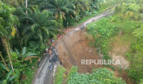 Foto udara warga melewati jembatan darurat yang baru dibangun akibat jalan longsor, di Nagari Gunung Padang Alai, Kabupaten Padang Pariaman, Sumatera Barat, Selasa (14/3/2023).  Jalan penghubung Kota Pariaman dengan Kabupaten Padang Pariaman dan Kabupaten Agam tersebut longsor akibat curah hujan tinggi dan warga membuat jembatan darurat untuk kendaraan roda dua serta pejalan kaki. ANTARA FOTO/Iggoy el Fitra/tom.