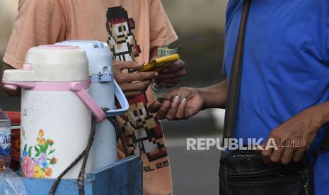 Interaksi pedagang kopi keliling dengan pembeli ditengah pandemi virus corona di Jakarta, Jumat (3/4/2020). Pemerintah pusat melalui Kementerian Keuangan tengah melakukan finalisasi skema pemberian BLT sebagai salah satu stimulus bagi masyarakat yang dirugikan akibat pandemi COVID-19 yang akan menyasar kepada 40 persen warga miskin yang paling berhak