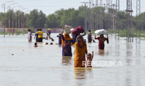 Pengungsi membawa barang-barang setelah mereka menyelamatkan barang-barang yang dapat digunakan dari rumah mereka yang dilanda banjir saat mereka menyeberangi daerah banjir di Jaffarabad, sebuah distrik di provinsi Baluchistan barat daya Pakistan, Sabtu, 27 Agustus 2022. Para pejabat mengatakan banjir bandang dipicu oleh hujan monsun lebat di sebagian besar Pakistan telah menewaskan hampir 1.000 orang dan membuat ribuan lainnya mengungsi sejak pertengahan Juni.