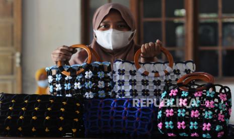 Seorang warga menunjukan tas dengan bahan dasar limbah gelas plastik yang telah jadi di Bakungan, Karangdowo, Klaten, Jawa Tengah, Rabu (29/9/2021). Kreativitas yang dilakukan kelompok ibu-ibu warga setempat dengan memanfaatkan limbah gelas plastik dijadikan bahan dasar membuat tas dan dompet tersebut memiliki nilai jual tinggi dari harga Rp120 ribu hingga Rp200 ribu tergantung tingkat kesulitan dan telah memenuhi permintaan pasar ke daerah Kalimantan, Surabaya dan Solo. 