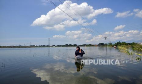 Seorang warga melintasi jalan yang terdampak banjir di Karangturi, Setrokalangan, Kaliwungu, Kudus, Jawa Tengah, Sabtu (7/1/2023). Sejumlah titik banjir di 29 desa sejak sepekan terakhir itu mulai berangsur surut dan beberapa pengungsi mulai kembali ke rumahnya. 