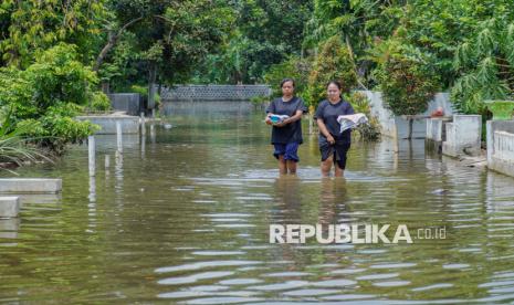 Warga melintasi genangan banjir akibat luapan sungai di Desa Rowokangkung, Lumajang, Jawa Timur, Jumat (22/11/2024). Pemkab Lumajang telah berkoordinasi dengan pihak terkait untuk menormalisasi sedimentasi sungai sepanjang 1,5 km penyebab banjir yang mengakibatkan 541 kepala keluarga di empat dusun terdampak. 