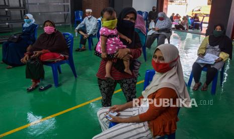 Sejumlah warga mengenakan masker dan menjaga jarak saat menunggu giliran pencairan bantuan sosial (Bansos) - ilustrasi