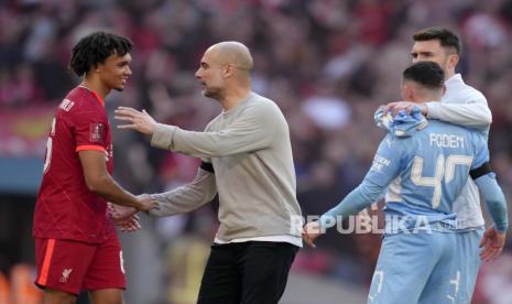 Pelatih kepala Manchester City Pep Guardiola berjabat tangan dengan pemain Liverpool Trent Alexander-Arnold, kiri, pada akhir pertandingan sepak bola semifinal Piala FA Inggris antara Manchester City dan Liverpool di stadion Wembley di London, Sabtu, 16 April 2022. Liverpool menang 3 2.