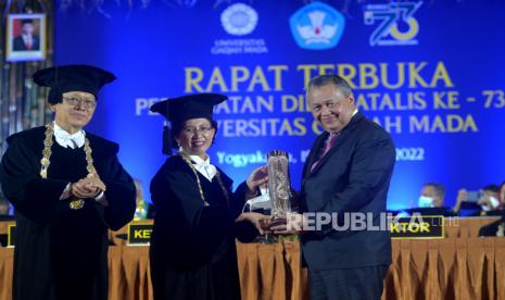 Rektor UGM Ova Emilia menyerahkan Anugerah HB IX kepada Gubernur BI Perry Warjiyo didampingi Ketua Dewan Guru Besar UGM Mochammad Maksum (kiri) saat acara Puncak Dies Natalis ke-73 Universitas Gajah Mada (UGM) di Graha Sabha Pramana, Kabupaten Sleman, Senin (19/12/2022). 