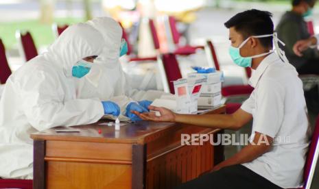 Petugas laboratorium kesehatan mengambil sampel darah peserta tes cepat Covid-19.