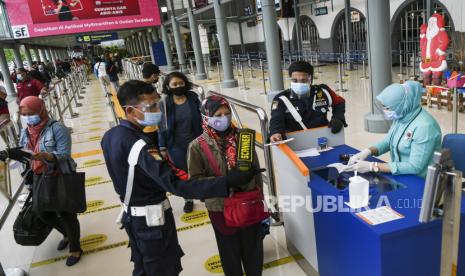 Petugas mengcek identitas dan surat bebas COVID-19 kepada calon penumpang Kereta Api (KA) di Stasiun Pasar Senen, Jakarta, Senin (21/12/2020). PT Kereta Api Indonesia (KAI) Persero jelang Natal dan Tahun Baru 2021 menerapkan protokol kesehatan ketat moda transportasi KA, mulai 22 Desember 2020 sampai 8 Januari 2021, yakni penumpang KA jarak jauh di Pulau Jawa diharuskan untuk menunjukkan hasil rapid test antigen atau tes PCR yang negatif sebagai syarat perjalanan naik kereta api. 