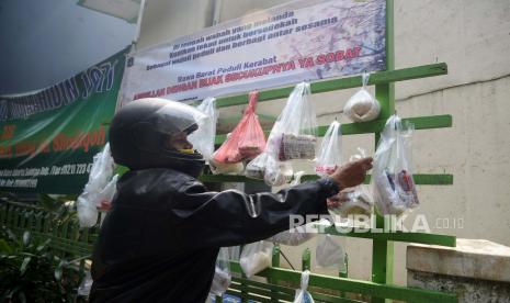 Warga mengambil kebutuhan pokok yang digantung di Tiang Berbagi Sedekah di Masjid Mujahidin, Ciragil, Jakarta, Kamis (14/5). Tiang berbagi sedekah yang berisi berbagai kebutuhan pokok ini merupakan wujud peduli dan berbagi antar sesama sekaligus bentuk gotong royong warga di masa pandemi Covid-19