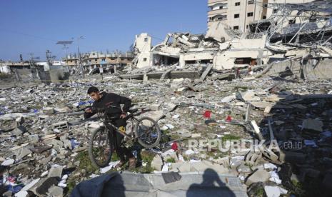 Seorang warga Palestina berjalan melewati kehancuran akibat pemboman Israel di kamp pengungsi Nusseirat di Jalur Gaza, Selasa, (16/1/2024).