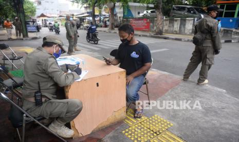 Petugas memproses warga yang terjaring operasi yustisi protokol Covid-19 di Kawasan Johar Baru, Jakarta, Ahad (22/11). Dalam oprasi tersebut sebanyak 20 warga menjalani hukuman kerja sosial karena abai menggunakan masker. Operasi yustisi terus dilakukan untuk mengingatkan warga agar menerapkan protokol kesehatan ketika berada di luar rumah. Prayogi/Republika. 