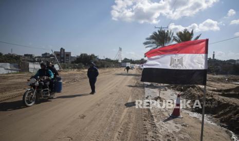 Warga Palestina mengibarkan bendera Mesir di sisi jalan di Beit Lahiya, Jalur Gaza utara, 25 Januari 2022. 