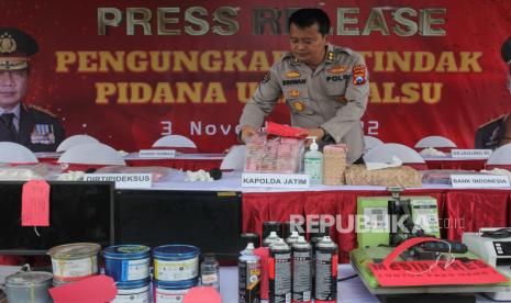 Polisi menata barang bukti saat ungkap kasus produksi serta peredaran uang palsu di Polda Jawa Timur, Surabaya, Jawa Timur, Kamis (3/11/2022). Polda Jawa Timur beserta Polres Kediri menangkap 11 tersangka atas kasus dugaan memproduksi serta mengedarkan uang palsu dan mengamankan sejumlah barang bukti beberapa diantaranya sejumlah mesin cetak dan ratusan lembar uang palsu. 