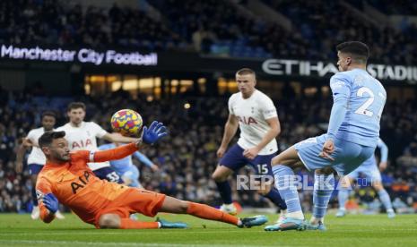 Penjaga gawang Tottenham Hugo Lloris, kiri, melakukan penyelamatan di depan Joao Cancelo dari Manchester City selama pertandingan sepak bola Liga Premier Inggris antara Manchester City dan Tottenham Hotspur, di stadion Etihad di Manchester, Inggris, Sabtu, 19 Februari 2022.