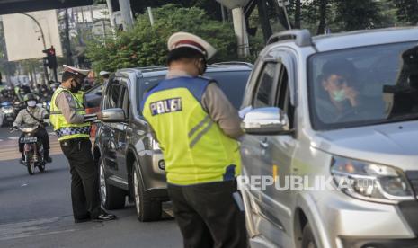 Anggota kepolisian saat menilang pengendara mobil dengan nomor pelat ganjil di Fatmawati, Jakarta, Senin (10/8). Direktorat Lalu Lintas Polda Metro Jaya kembali menerapkan sanksi tilang terhadap kendaraan roda empat yang melanggar peraturan ganjil genap di masa Pembatasan Sosial Berskala Besar (PSBB) transisi. Republika/Putra M. Akbar