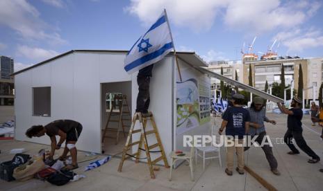 Aktivis sayap kanan Israel dari Gerakan Pemukiman Nachala mendirikan bangunan sementara sebagai bagian dari protes yang menyerukan pendirian pemukiman Yahudi baru di Tepi Barat yang diduduki, di Habima Square di Tel Aviv, 12 Juli 2022. Mahkamah Agung Israel pada hari Rabu 27 Juli 2022, telah membuka jalan bagi penduduk pos terdepan permukiman Yahudi Tepi Barat Mitzpe Kramim untuk tetap tinggal di rumah mereka, membatalkan perintah penggusuran sebelumnya yang menetapkan bahwa tanah tersebut telah dibeli secara ilegal. Warga Palestina khawatir ini bisa menjadi preseden untuk perselisihan di masa depan atas permukiman Yahudi yang dibangun di atas tanah Palestina milik pribadi.