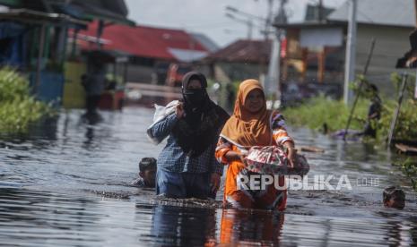 Warga melintas di permukiman sekitar rumahnya yang terendam banjir di Jalan Anoi Ujung, Palangkaraya, Kalimantan Tengah.