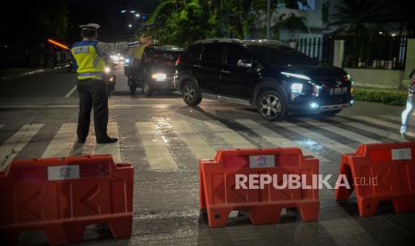 Petugas kepolisian mengatur lalu lintas saat penutupan akses jalan selama PPKM Darurat.