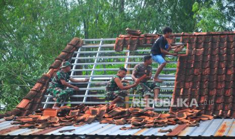 Warga bersama TNI bergotong royong memperbaiki atap rumah yang rusak akibat diterjang angin puting beliung di Desa Bologarang, Penawangan, Grobogan, Jawa Tengah, Rabu (10/1/2024). Bencana angin puting beliung yang menerjang tiga Desa yaitu Desa Sedadi, Bologarang dan Termas pada Selasa (9/1) petang itu mengakibatkan satu sekolah dan mushola rusak serta ratusan rumah lainnya rusak berat hingga ringan. 