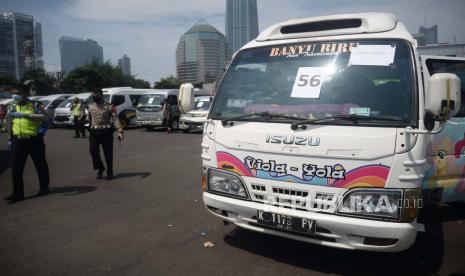 Seorang polisi melintas di depan mobil travel gelap yang terjaring dalam operasi khusus di titk penyekatan di Polda Metro Jaya, Jakarta, Senin (11/5). Dalam kurun waktu tiga hari operasi khusus tersebut, yakni mulai 8-10 Mei, Polda Metro Jaya mengamankan 202 kendaraan travel gelap yang mencoba mengangkut pemudik ke luar dari Jakarta