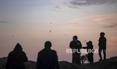 Sebuah keluarga Palestina di pantai saat matahari terbenam dekat kamp pengungsi Rafah, Jalur Gaza selatan, (11/2/2024).