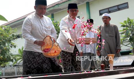 Bakal calon presiden (bacapres) Anies Baswedan (tengah) menaburkan bunga saat berziarah ke makam pendiri Nahdlatul Ulama KH Bisri Syansuri di Pondok Pesantren Mambaul Ma