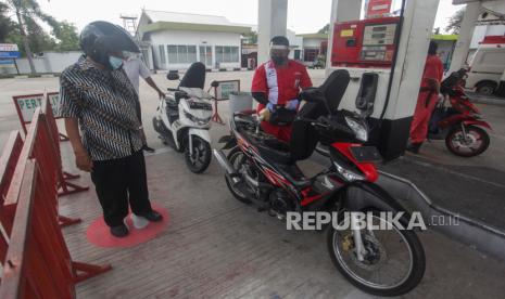 Petugas melayani pengendara motor dengan menjaga jarak fisik (physical distancing) saat pengisian BBM di area SPBU. 