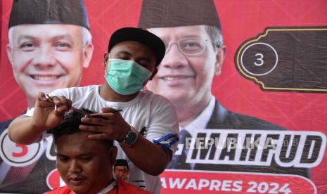 Tukang pangkas rambut memotong rambut warga saat acara Ayo Nyukur Biar Sekeren Ganjar Mahfud di Kawasan Kwitang, Jakarta, Kamis (28/12/2023). Relawan Ganjar-Mahfud dan didukung oleh Tim Pemenangan Daerah (TPD) Ganjar-Mahfud DKI Jakarta menyelenggarakan kegiatan ayo nyukur yang diikuti lebih dari 100 orang mulai laki-laki dewasa, paruh baya, lanjut usia hingga perempuan.