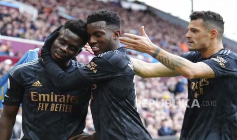 Pemain Arsenal, Bukayo Saka (kiri) berselebrasi dengan Eddie Nketiah  dan Granit Xhaka setelah mencetak gol pembuka timnya pada pertandingan sepak bola Liga Premier Inggris antara Aston Villa dan Arsenal di Villa Park di Birmingham, Inggris, Sabtu (18/2/2023). 